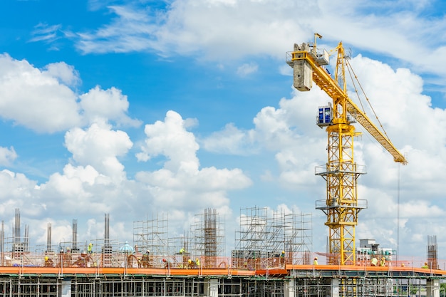 Construction cranes and high-rise building under construction against blue sky.