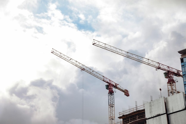 Construction cranes work on creation site against sky\
background