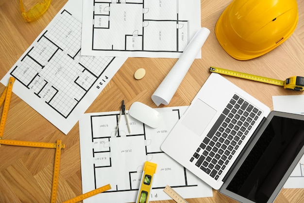 construction drawings laptop and tools on wooden table flat lay