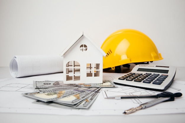 Construction drawings with helmet money and model of house cost of building