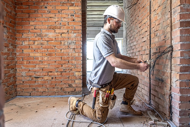 A construction electrician cuts a voltage cable during a repair.