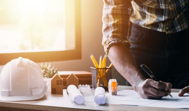 Construction engineer working at blueprint to build large commercial buildings in office Engineering tools and construction concept