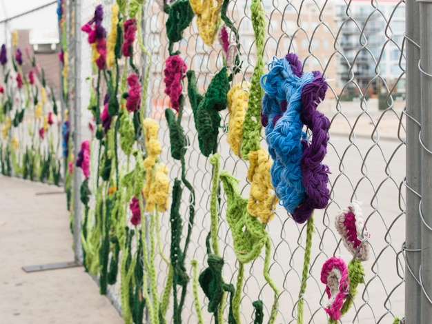 Construction fence covered with crocheted garden creatures like bugs and flowers by the Ladies Fancywork Society. Construction site of the Union Station in Denver, Colorado.