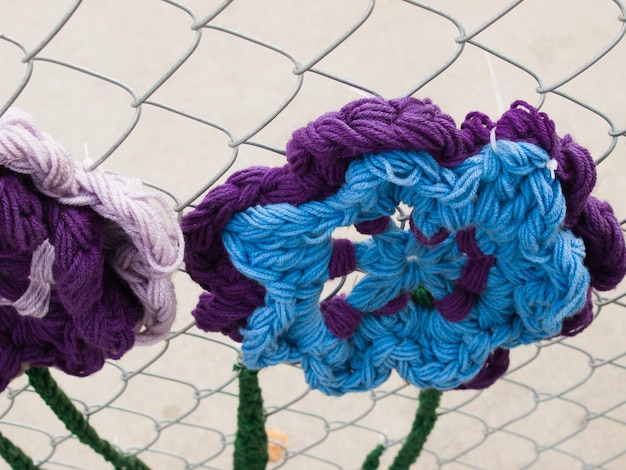 Construction fence covered with crocheted garden creatures like bugs and flowers by the ladies fancywork society. construction site of the union station in denver, colorado