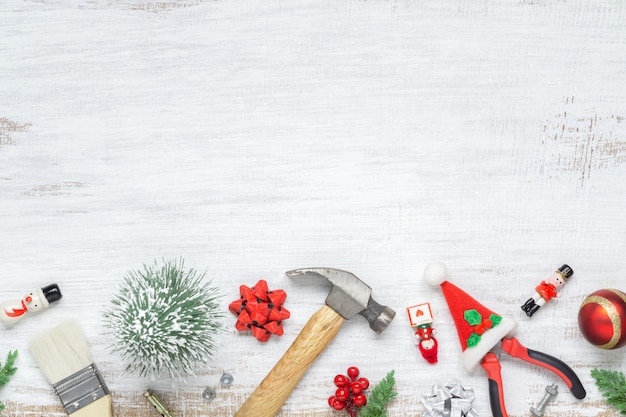 Construction handy tools with Christmas ornament on white wood