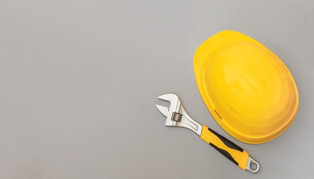 Construction helmet and adjustable wrench on a gray background