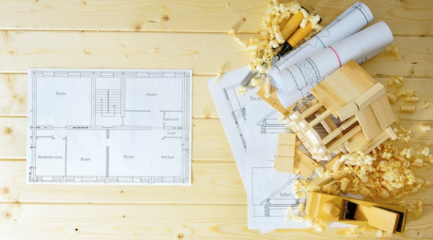 Construction house. Joiner's works. Drawings for building, small wooden house and working tools on wooden background.