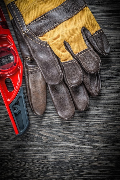 Кожаные защитные перчатки на строительном уровне на деревянной доске