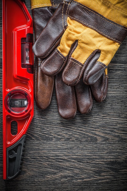 Construction level pair of working gloves on wooden board