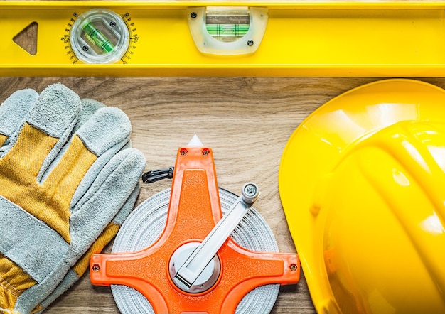 Foto guanti di sicurezza a livello di costruzione che misurano il casco da costruzione a nastro su tavola di legno