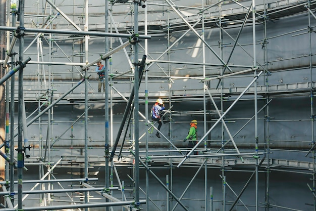 Photo construction male workers tank oil installing scaffolding in side tank confined spec