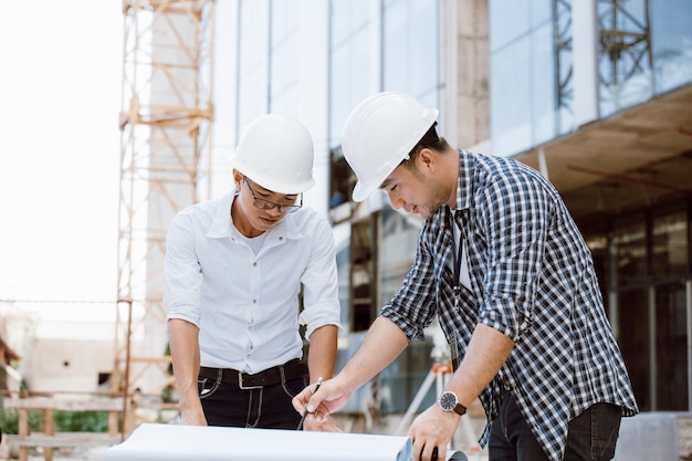 Construction manager and engineer team checking plan on construction site. Theodolite transit equipment. Engineer team. Working on building site.