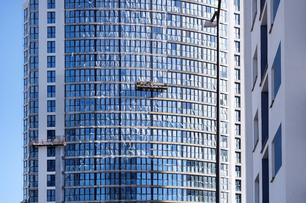 Construction of modern buildings workers install windows in cradles high quality photo