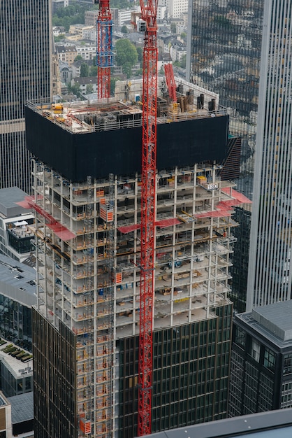 Construction of a modern high-rise skyscraper with cranes in the center of the metropolis. Construction