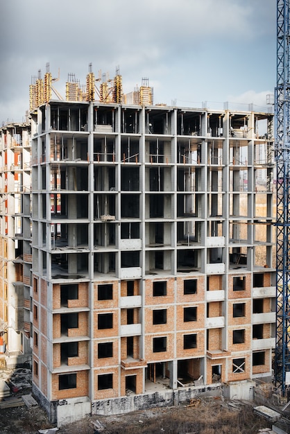 Construction of a modern high-rise skyscraper with cranes in the center of the metropolis