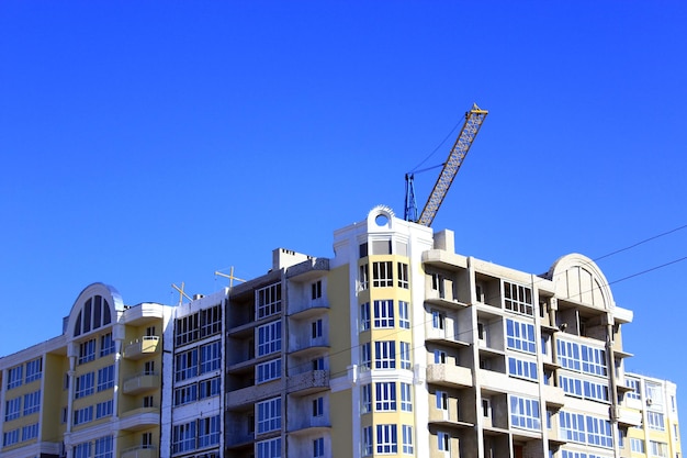 construction of multistorey modern house with hoisting crane on the blue sky background