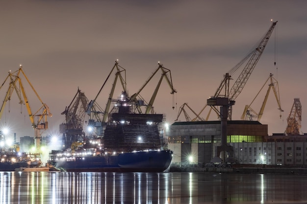 The construction of nuclear icebreakers at night cranes of the Baltic shipyard in a frosty winter