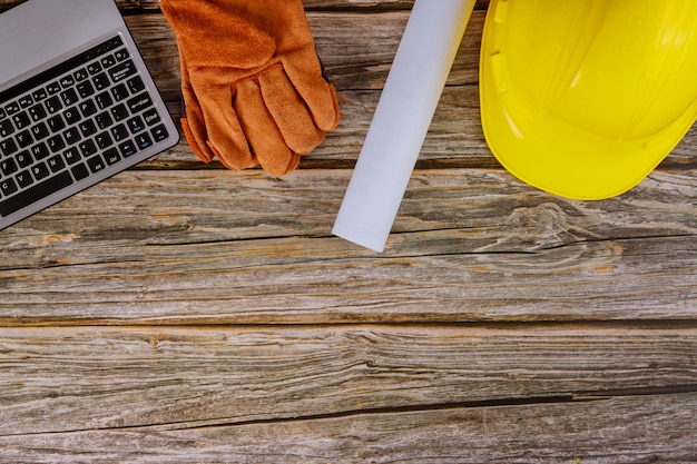 Construction office working computer keyboard with blueprints in the set of protective workwear in yellow hard hat protective gloves