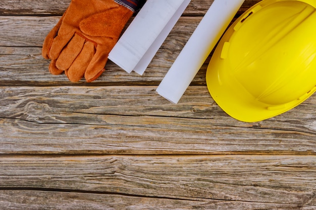 Construction office working with blueprints in the set of protective workwear in yellow hard hat protective gloves