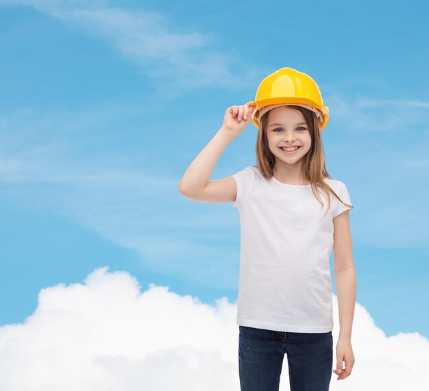 construction and people concept - smiling little girl in protective helmet