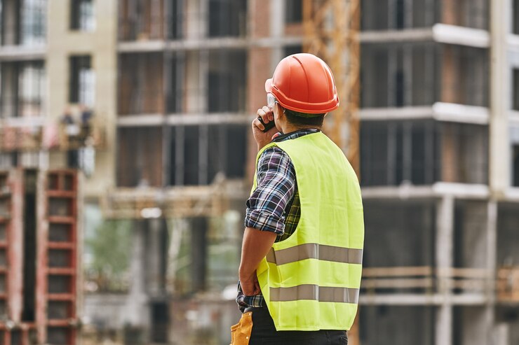 Photo construction process back view of professional young builder in working uniform red protective