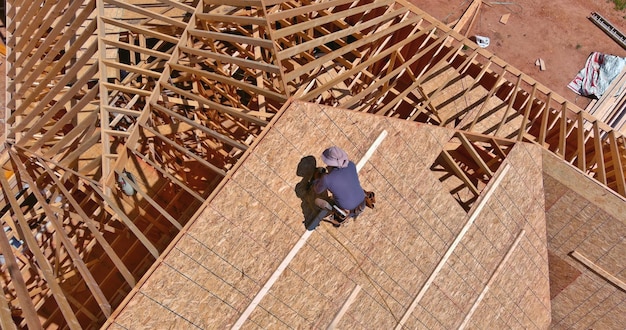 Construction roofer carpenter worker nailing wood plywood with roof installation