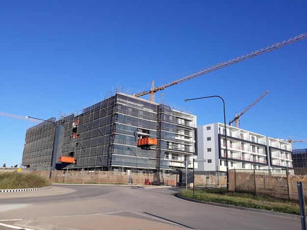 Construction site by building against clear blue sky