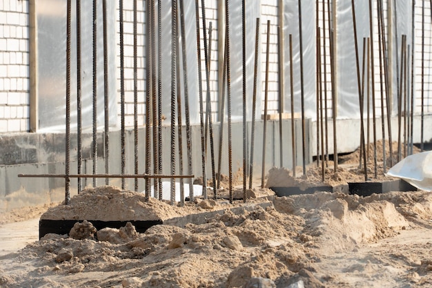 건설 현장 새 건물 건설 금속 메쉬로 보강된 구조의 미완성 건물 진흙 많은 모래