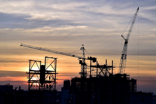 Cantiere. le gru a torre silhouette costruiscono grandi edifici residenziali in cantiere.