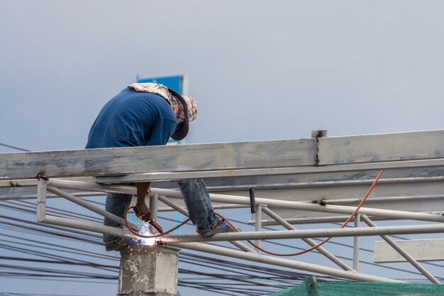 In the construction site, the welding workers at work at top roof.