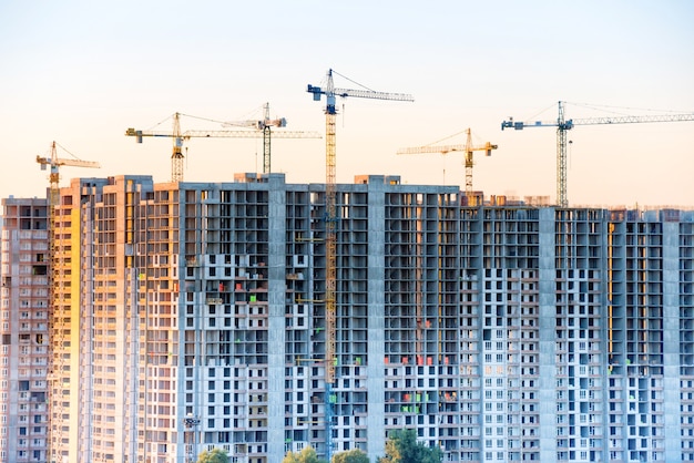 Construction site with building cranes at sunset