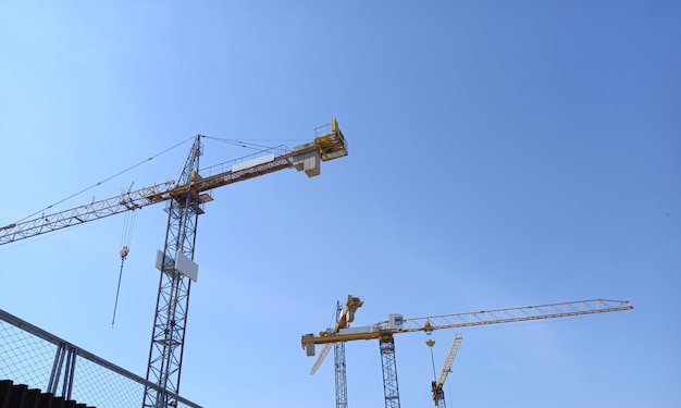 A construction site with cranes and building under clear blue sky