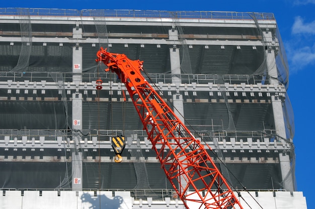 Photo construction site with rising up building and red crane foreground