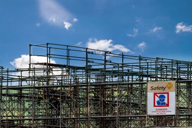 Cantiere con la torre dell'impalcatura e la costruzione dell'etichetta di avvertimento, armatura per la fabbrica della costruzione