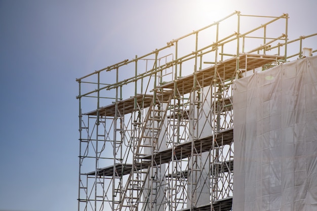 Cantiere con la torre dell'impalcatura e costruzione dell'etichetta di avvertimento con il cielo, armatura per la fabbrica della costruzione