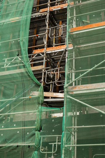 Construction site with unfinished residential building outdoors covered with protective fence Housing construction apartment block