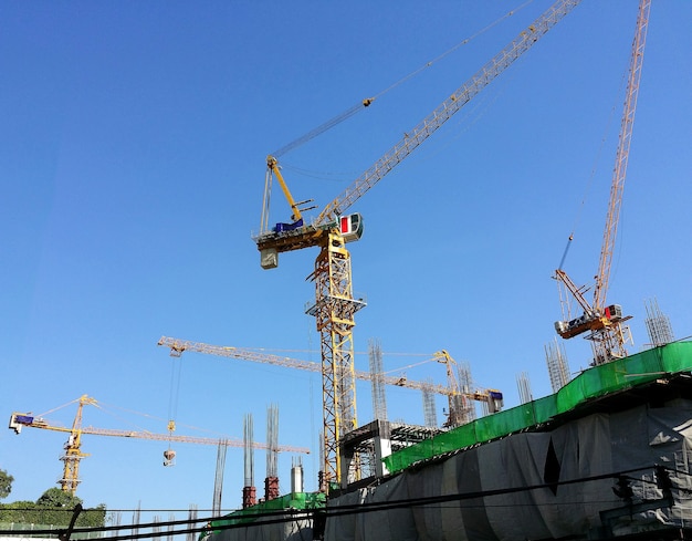 Construction site and yellow crane and building and blue sky.