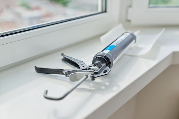 Construction syringe with silicone sealant on the windowsill