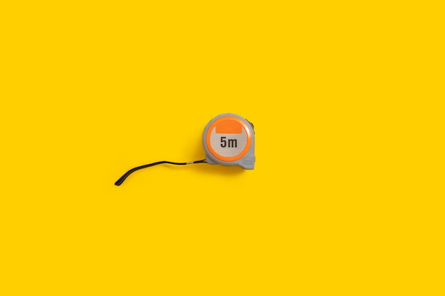 Construction tape measure on a yellow background Top view flat lay