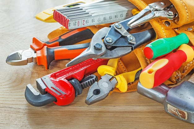 Construction tooling in leather tool belt on wooden board