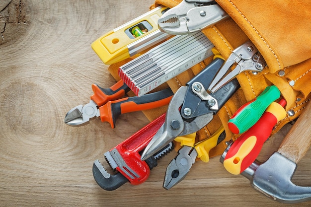 Construction tooling in tool belt on wooden board