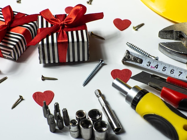 Construction tools and gifts on white background with small red hearts