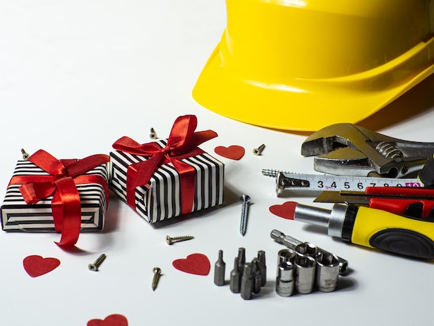 Construction tools and gifts on white background with small red hearts