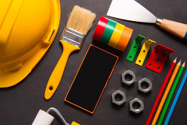 Construction tools and smart phone on black background