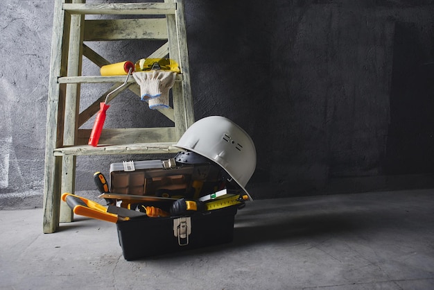 Construction tools and stepladder on a black wall background. Repairs