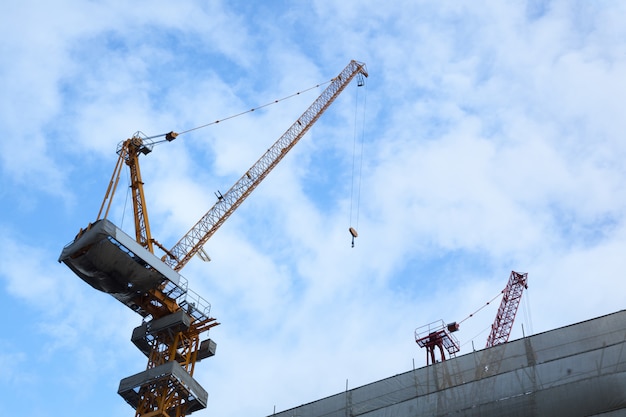 Construction tower cranes lifting cargo on blue sky