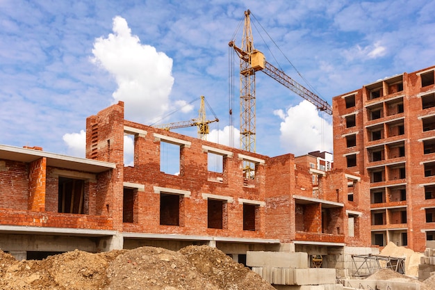 Foto costruzione della parete di una gru a torre multipiano della casa di mattoni su un cantiere