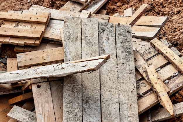 Construction waste after dismantling the formwork of a reinforced concrete foundation Utilization of construction waste Old boards beams and formwork panels at a construction site