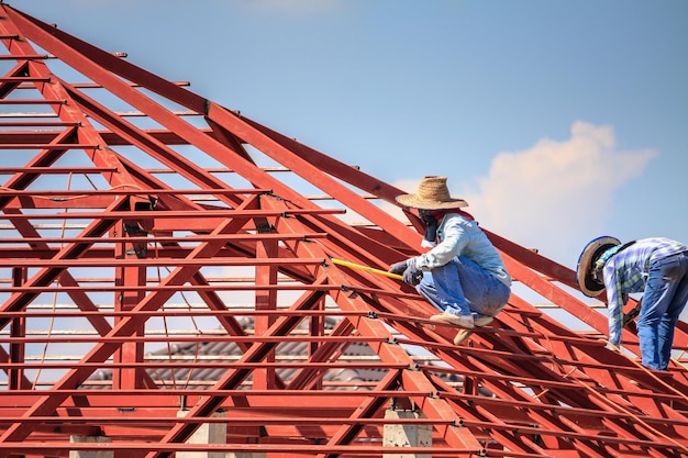 Construction welder workers installing steel frame structure of the house roof
