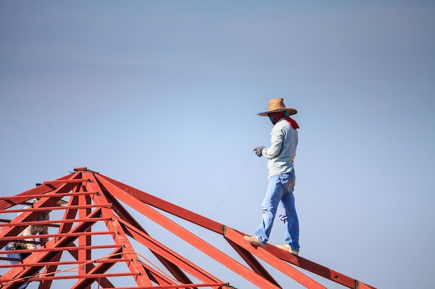 Construction welder workers installing steel frame structure of the house roof